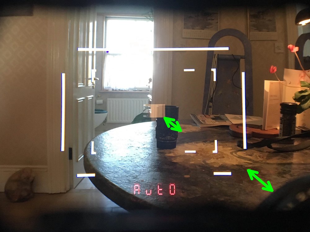   Leica M10-P viewfinder; frame lines and focusing patch move down and to the right, for “parallax correction”, as focused closer onto the lens standing on the table.  